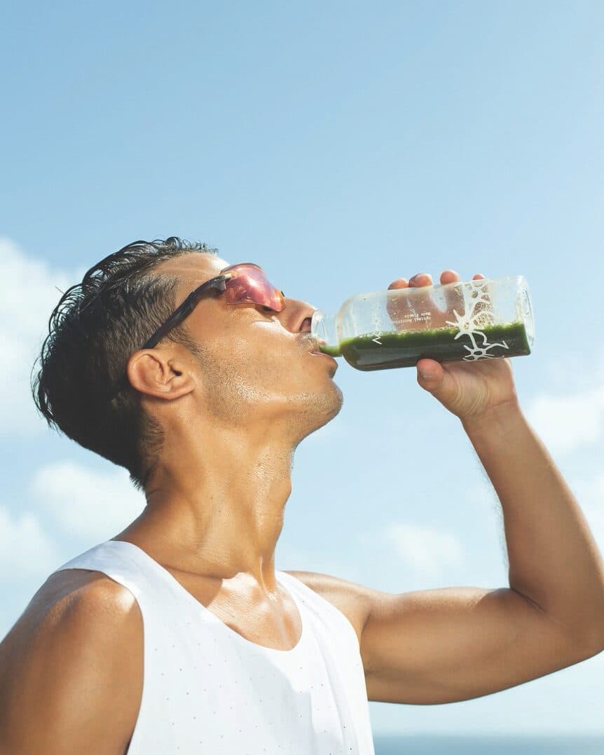Athlete drinking a green MatchUP matcha outdoors under a blue sky